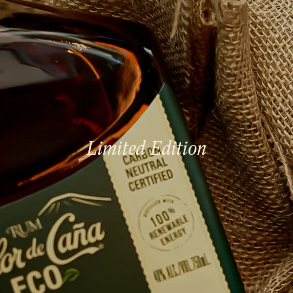 A close-up of a dark glass bottle with amber liquid, a dark green label, and a cream-colored 'Carbon Neutral Certified' sticker, nestled in a brown burlap sack. A white text overlay reads 'Limited Edition'.