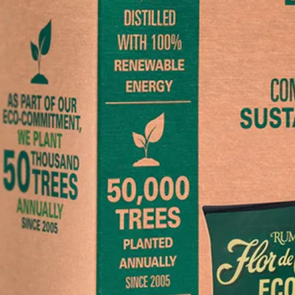 Close-up of a brown kraft paper label with green and beige text, including '50,000 TREES PLANTED ANNUALLY SINCE 2005' and 'DISTILLED WITH 100% RENEWABLE ENERGY'.