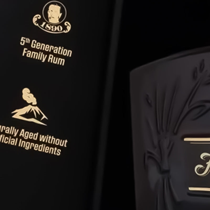 Close-up of a dark bottle with gold text and branding on a black background