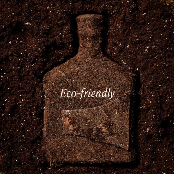 A dark brown bottle-shaped object embedded in soil, with the words 'Eco-friendly' printed across the front in white text.
