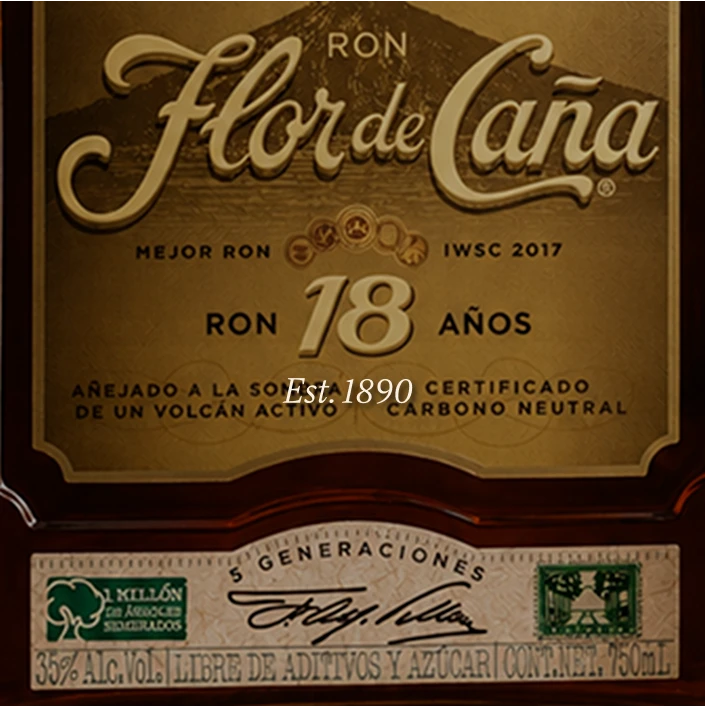 Close-up of a Ron Flor de Cana 18-year-old rum bottle label, showing the brand name in elegant gold lettering on a dark brown background with additional Spanish text and certification details.